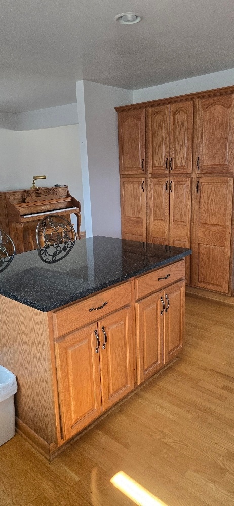 kitchen featuring dark stone counters, brown cabinetry, light wood finished floors, and a center island