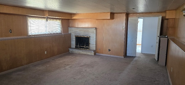 unfurnished living room with carpet flooring, a fireplace, and wood walls