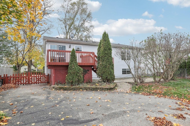 back of house with a gate, a wooden deck, and fence