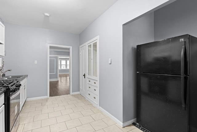 8025 S Evans Ave, Chicago, IL 60619 - kitchen with baseboards, stainless steel gas range, freestanding refrigerator, a sink, and white cabinets
