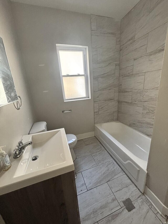 bathroom with baseboards, marble finish floor, toilet, vanity, and shower / tub combination