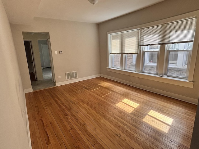 unfurnished room featuring baseboards, visible vents, and light wood-style floors