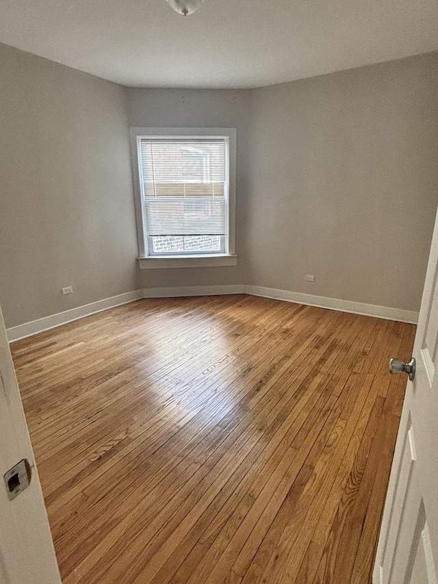 spare room featuring hardwood / wood-style floors and baseboards