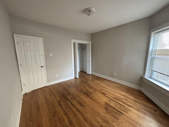 unfurnished bedroom featuring hardwood / wood-style floors, a closet, and baseboards