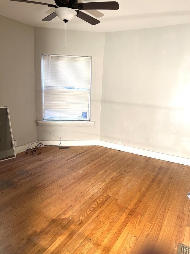 unfurnished room with hardwood / wood-style floors, a ceiling fan, baseboards, and visible vents