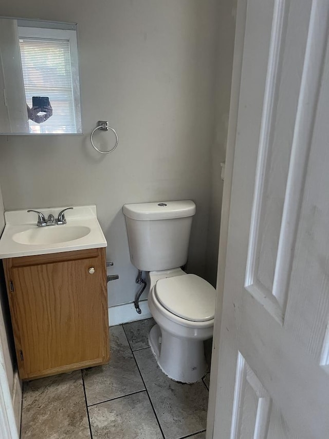 half bathroom with tile patterned floors, toilet, and vanity
