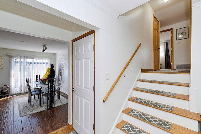 staircase with crown molding, wood finished floors, and baseboards