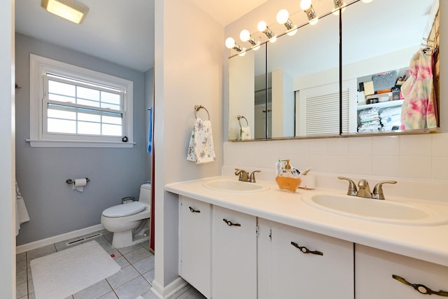 bathroom with a sink, toilet, double vanity, and tile patterned floors