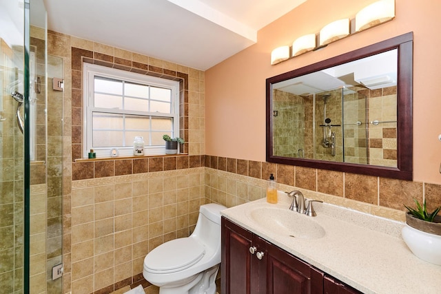 full bathroom featuring a tile shower, toilet, tile walls, and vanity