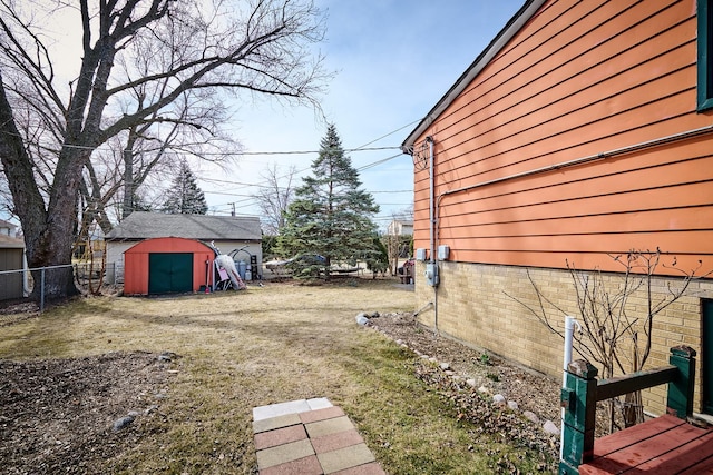 view of yard featuring fence, an outdoor structure, driveway, and a shed