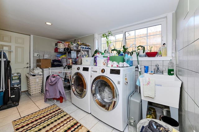 laundry room with washing machine and dryer, light tile patterned floors, laundry area, tile walls, and a sink