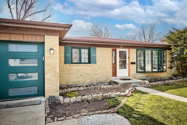 doorway to property featuring brick siding and an attached garage