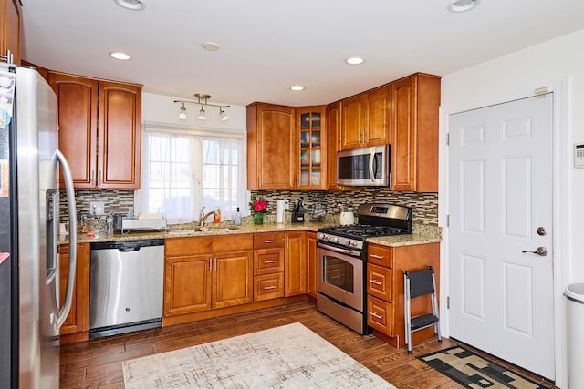 kitchen with dark wood-style floors, brown cabinets, appliances with stainless steel finishes, and a sink