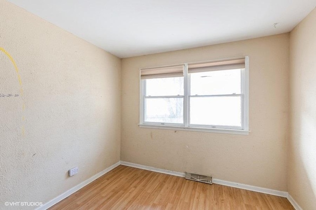 spare room featuring baseboards, visible vents, and light wood-type flooring