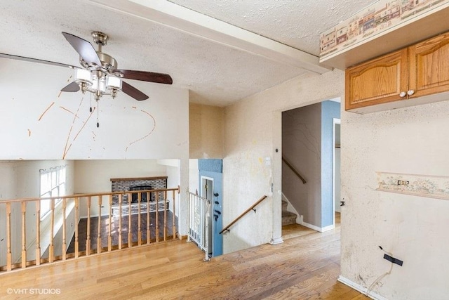 hall with stairway, light wood-style flooring, and a textured ceiling