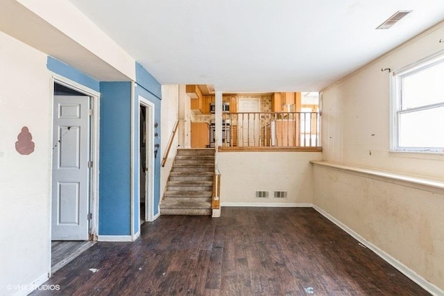 unfurnished living room with stairs, wood finished floors, visible vents, and baseboards