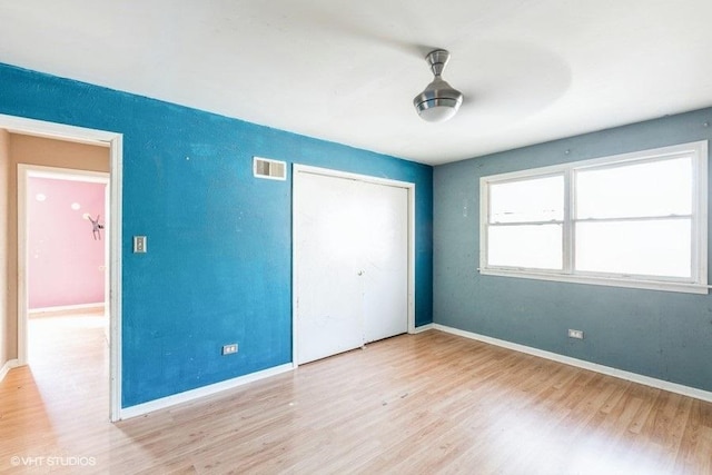 unfurnished bedroom with visible vents, baseboards, a closet, and wood finished floors