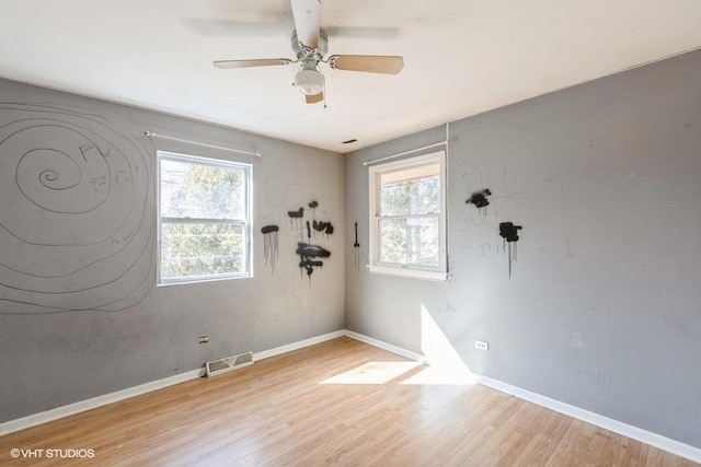 spare room featuring a ceiling fan, wood finished floors, visible vents, and baseboards