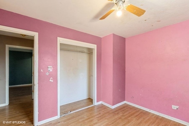 unfurnished bedroom featuring wood finished floors, baseboards, a closet, and ceiling fan