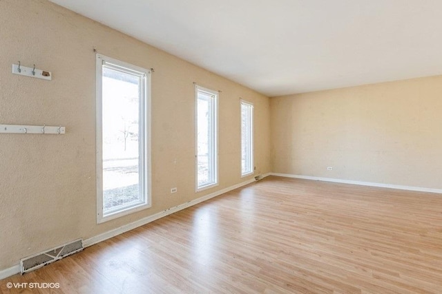 unfurnished room with light wood-style flooring, baseboards, and visible vents