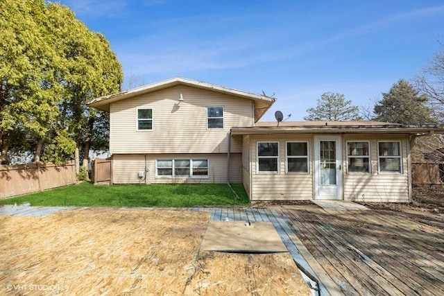 rear view of house featuring a yard, a deck, and fence