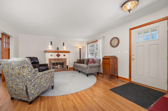 living area featuring a brick fireplace, wood finished floors, and baseboards