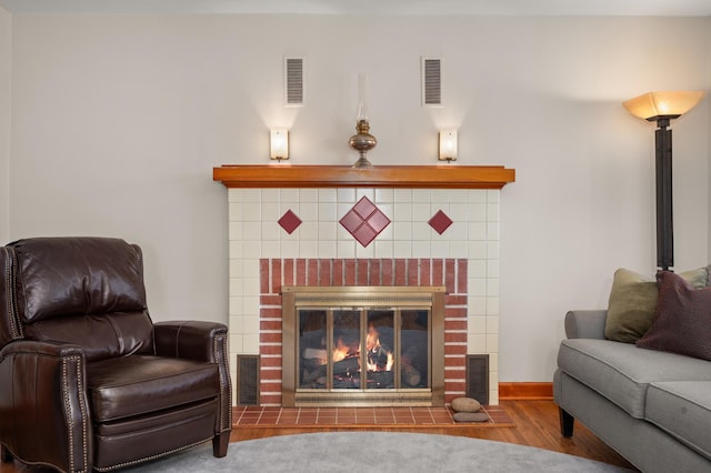 interior space featuring wood finished floors, visible vents, and a tile fireplace