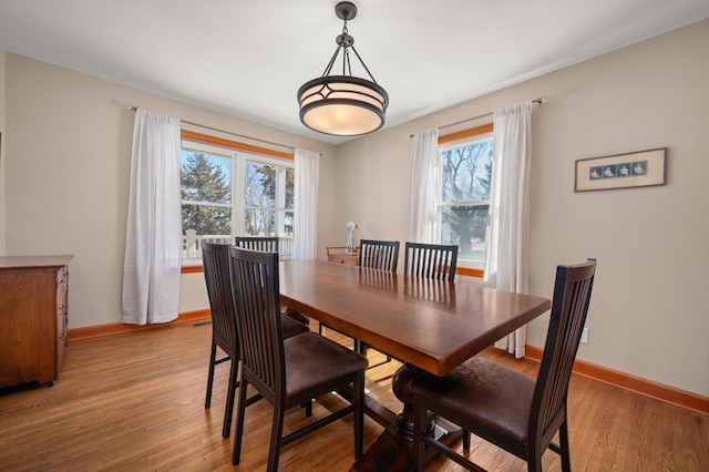 dining space featuring a wealth of natural light, light wood-type flooring, and baseboards