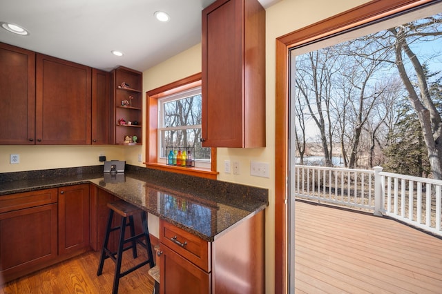 kitchen featuring recessed lighting, dark stone countertops, light wood-type flooring, and open shelves