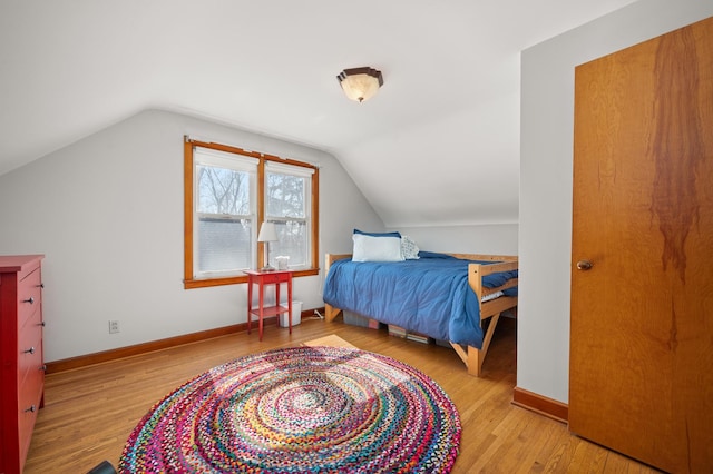 bedroom featuring baseboards, wood finished floors, and vaulted ceiling