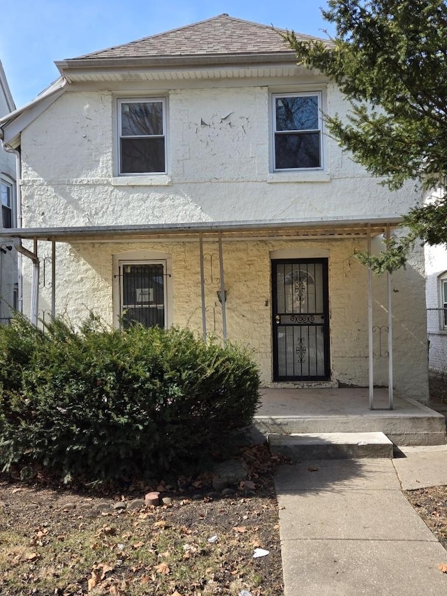 view of front of property featuring stucco siding, a porch, and a shingled roof