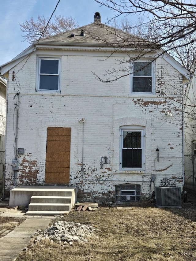 view of home's exterior featuring brick siding, cooling unit, and a chimney