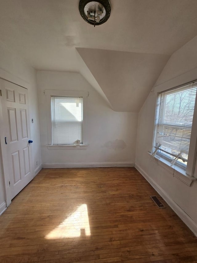 additional living space featuring vaulted ceiling, baseboards, visible vents, and wood finished floors