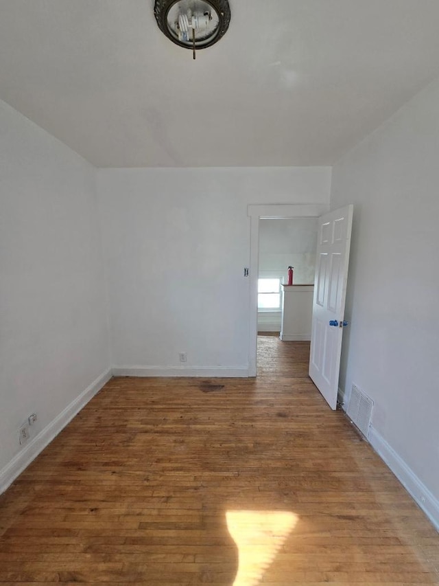 unfurnished room featuring visible vents, baseboards, and wood finished floors