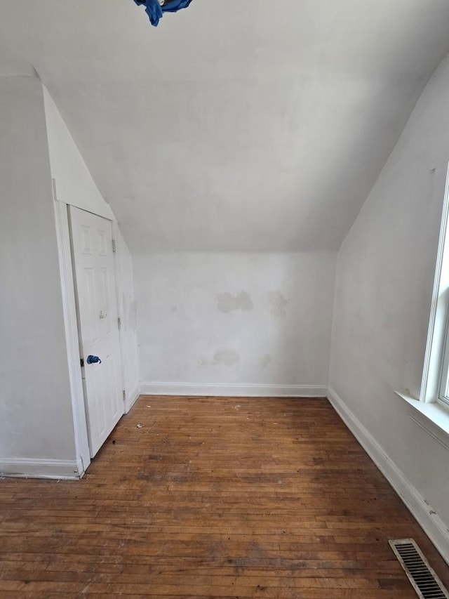 additional living space featuring baseboards, visible vents, wood-type flooring, and lofted ceiling