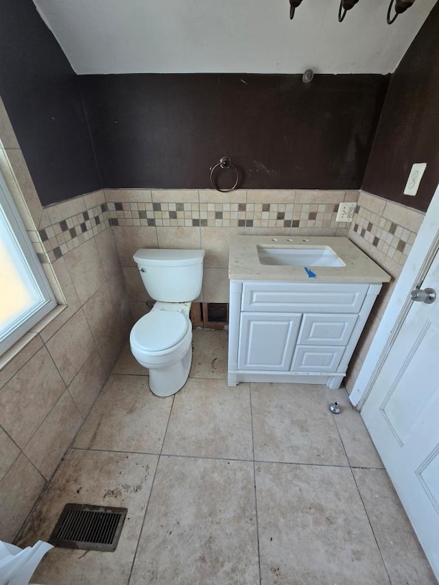 bathroom featuring tile patterned floors, visible vents, toilet, tile walls, and vanity