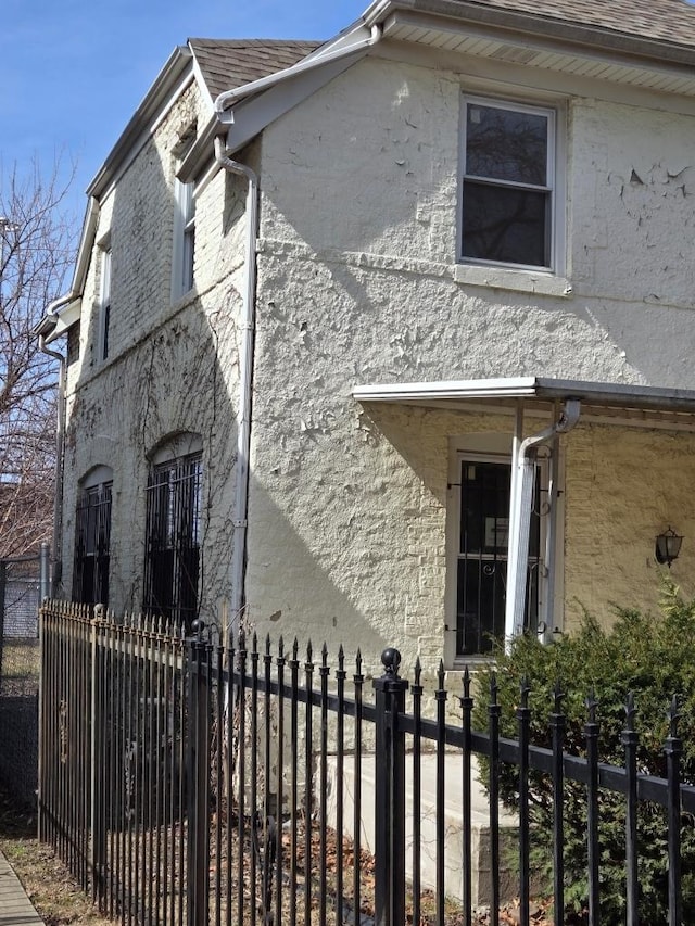 view of side of property featuring a fenced front yard and roof with shingles