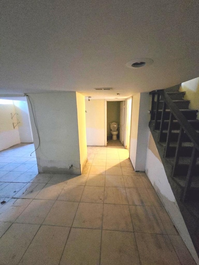 hallway with light tile patterned floors, stairway, and visible vents