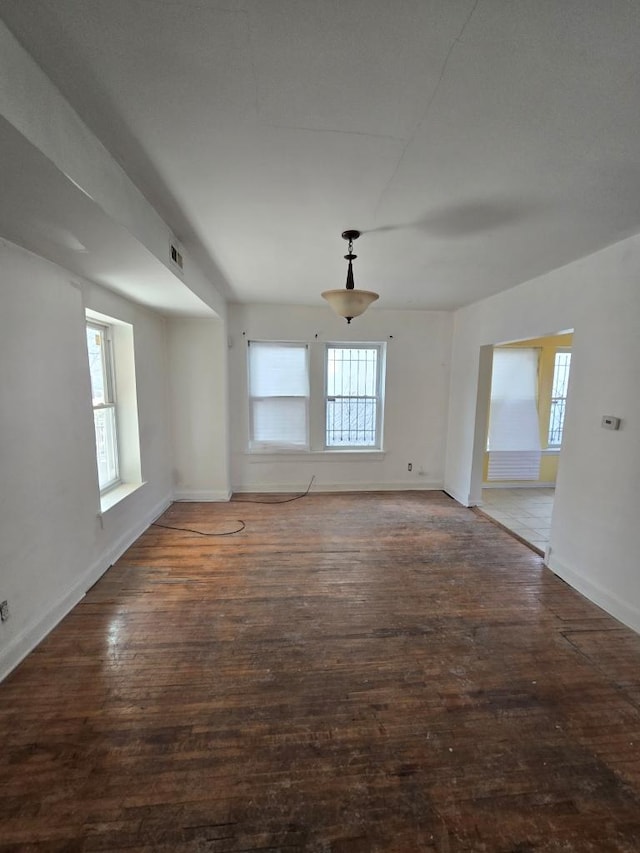 empty room featuring visible vents, baseboards, and wood finished floors