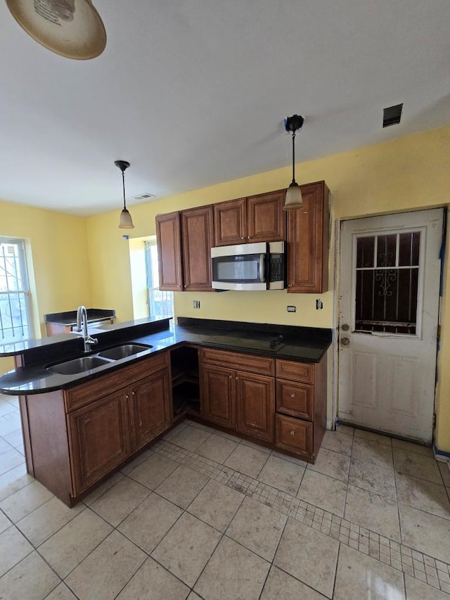 kitchen featuring stainless steel microwave, a healthy amount of sunlight, dark countertops, and a sink