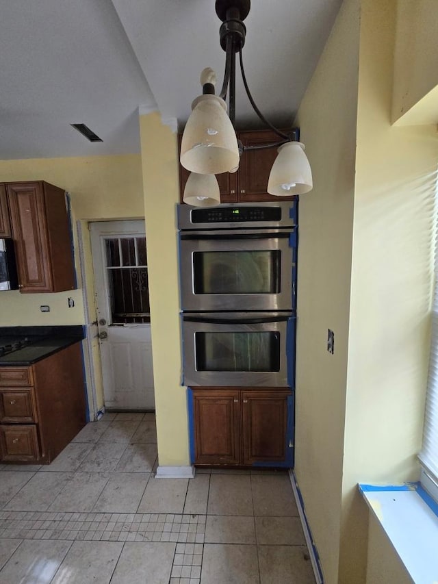 kitchen with light tile patterned floors, baseboards, visible vents, appliances with stainless steel finishes, and dark countertops