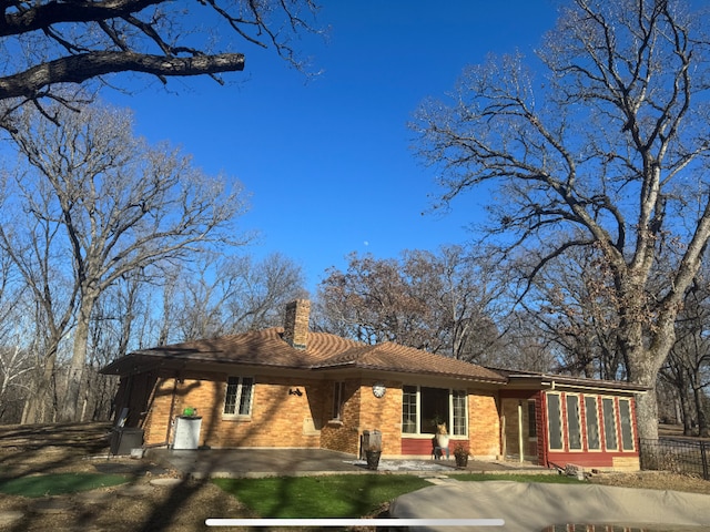 view of front of house with brick siding, driveway, and a chimney