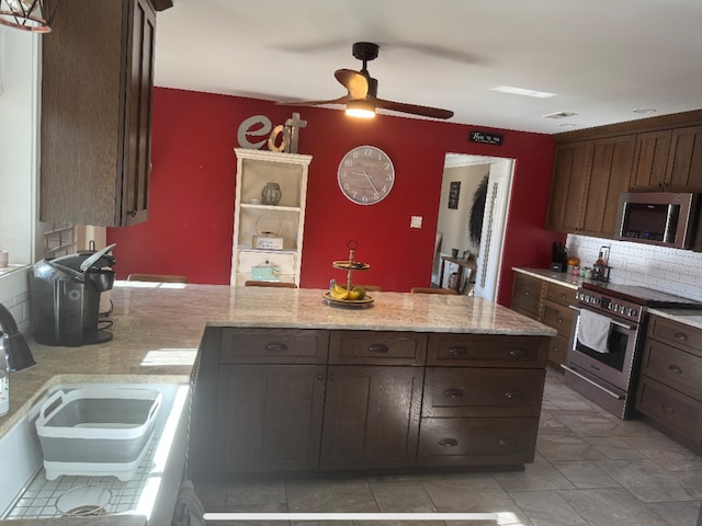 kitchen with a peninsula, a sink, dark brown cabinets, appliances with stainless steel finishes, and tasteful backsplash