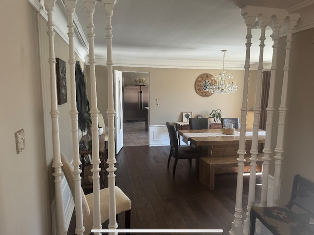 dining area with crown molding, a chandelier, a wainscoted wall, a decorative wall, and dark wood-style flooring