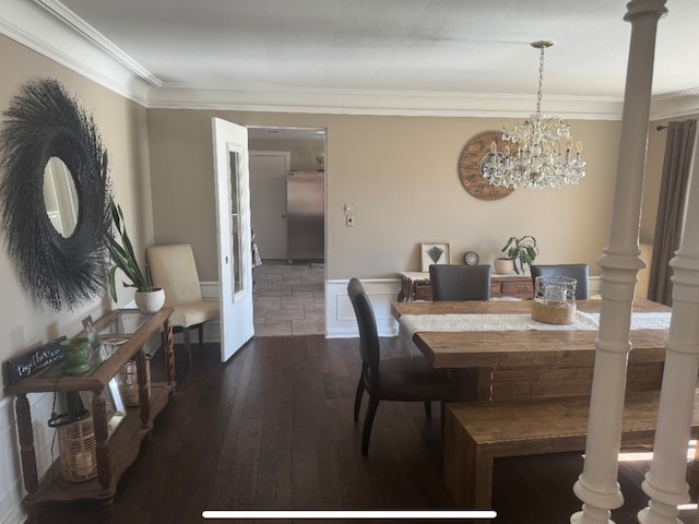 dining space featuring dark wood-style floors, crown molding, and ornate columns