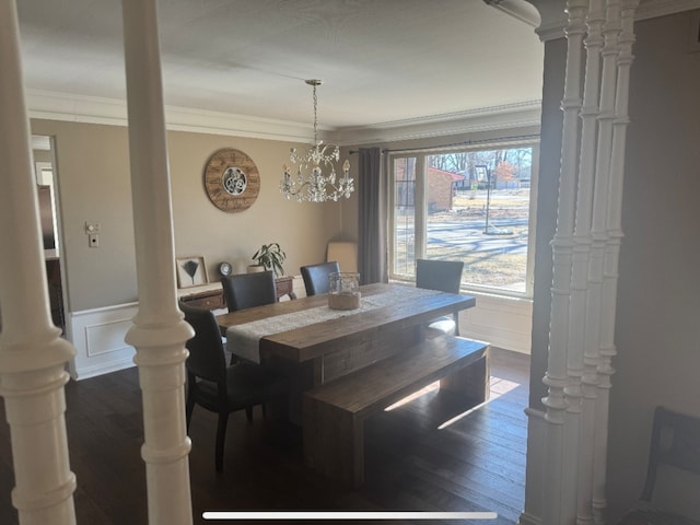 dining area featuring a decorative wall, wainscoting, crown molding, decorative columns, and dark wood-style flooring