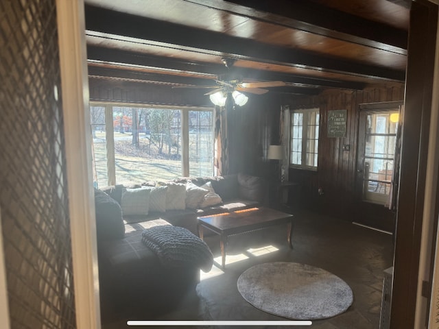 living room featuring beamed ceiling, wood walls, wood ceiling, and ceiling fan