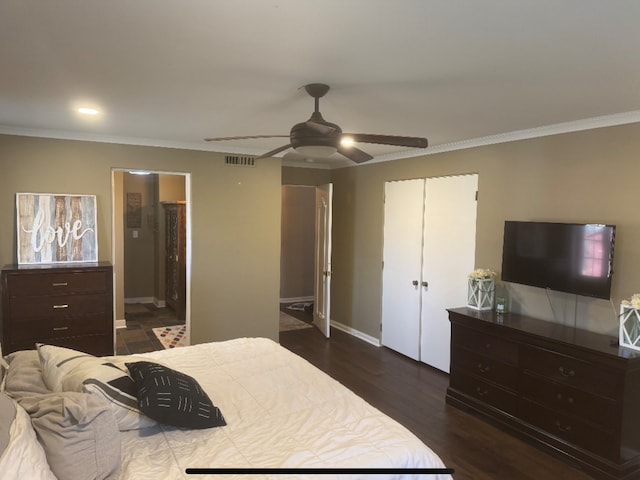 bedroom with visible vents, dark wood-type flooring, a closet, crown molding, and baseboards