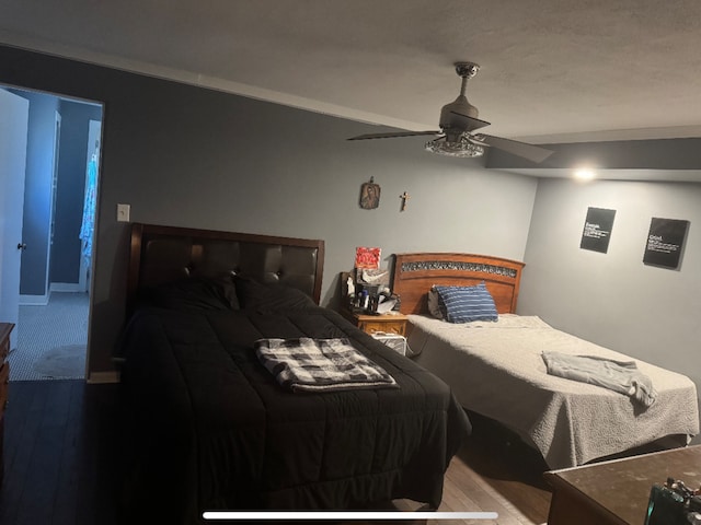 bedroom featuring a ceiling fan, crown molding, and wood finished floors