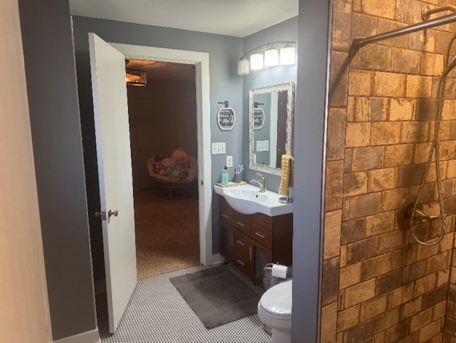 bathroom with a tile shower, toilet, and vanity